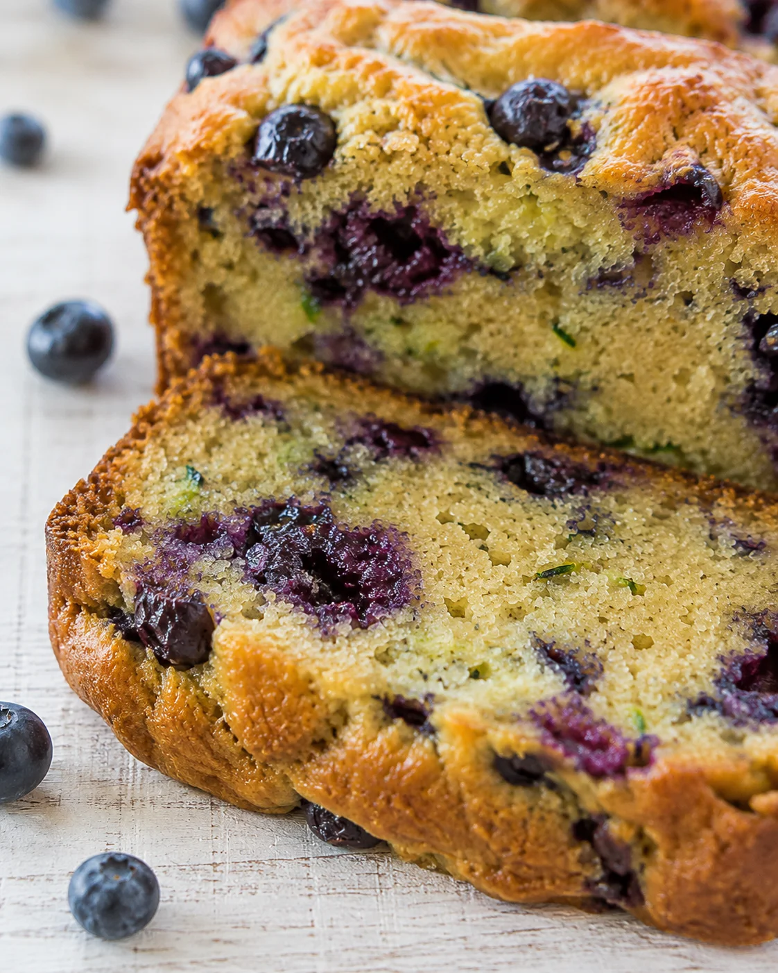 Blueberry Zucchini Bread Freshly baked blueberry zucchini bread with blueberries on top and sliced open