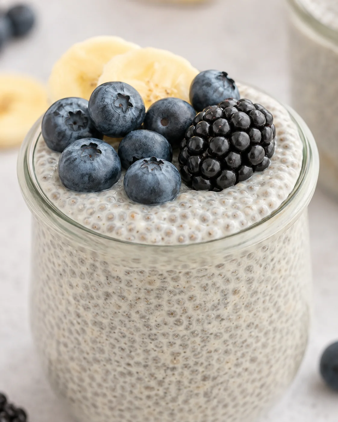Creamy vanilla chia pudding topped with blueberries and blackberries in a glass jar.