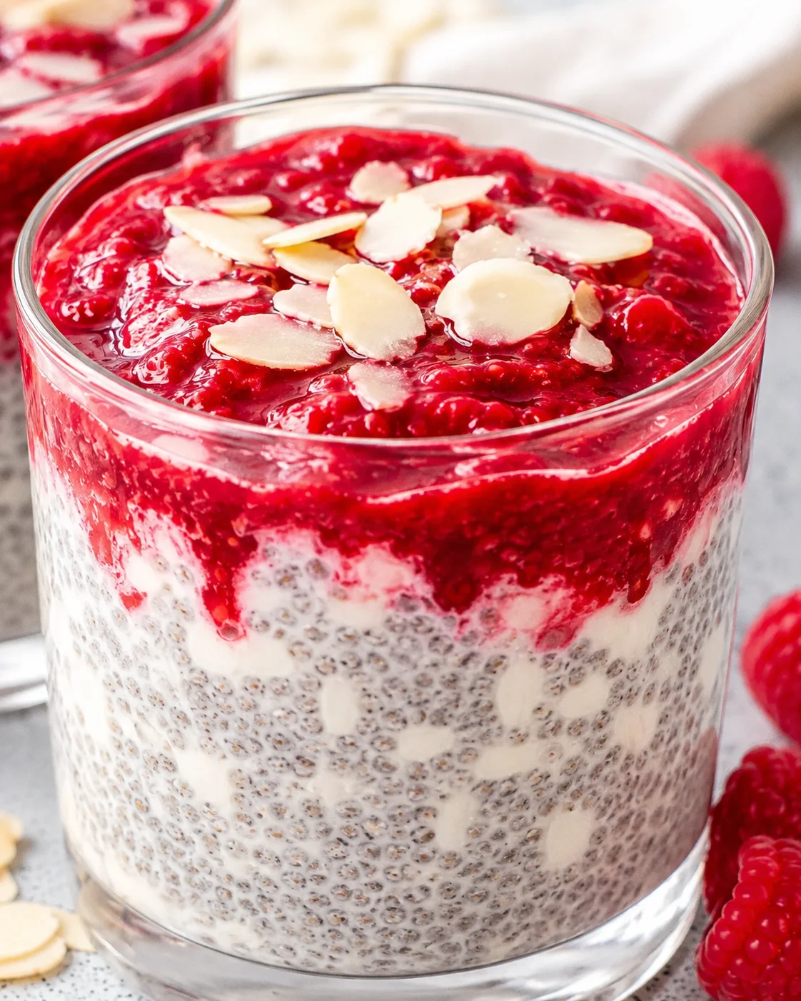 Close-up of raspberry chia pudding topped with almond slices in a glass
