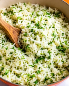 Bowl of cilantro lime rice being stirred with a wooden spoon