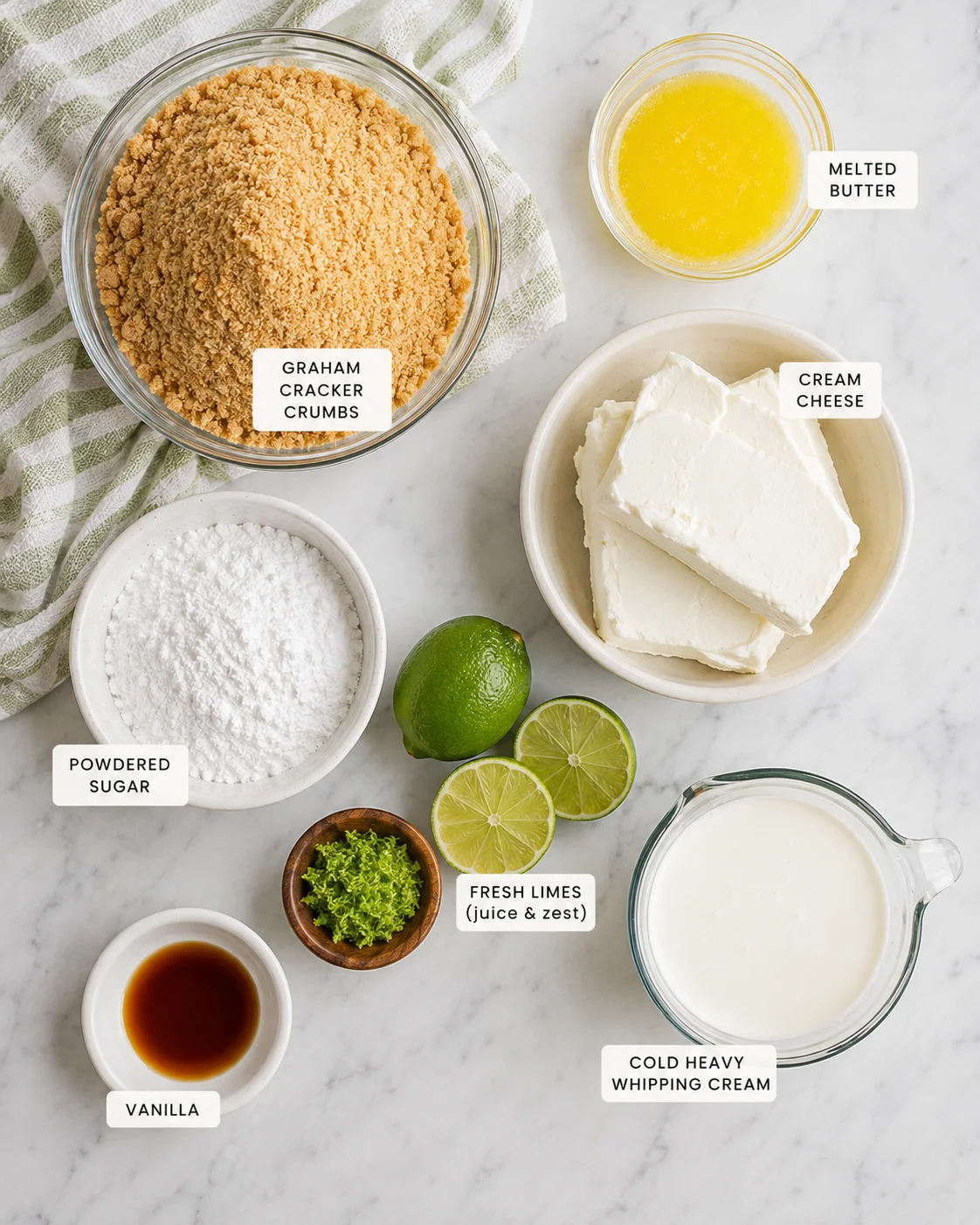 Top-down layout of ingredients for no bake Key Lime Cheesecake including graham crumbs, cream cheese, limes and heavy cream