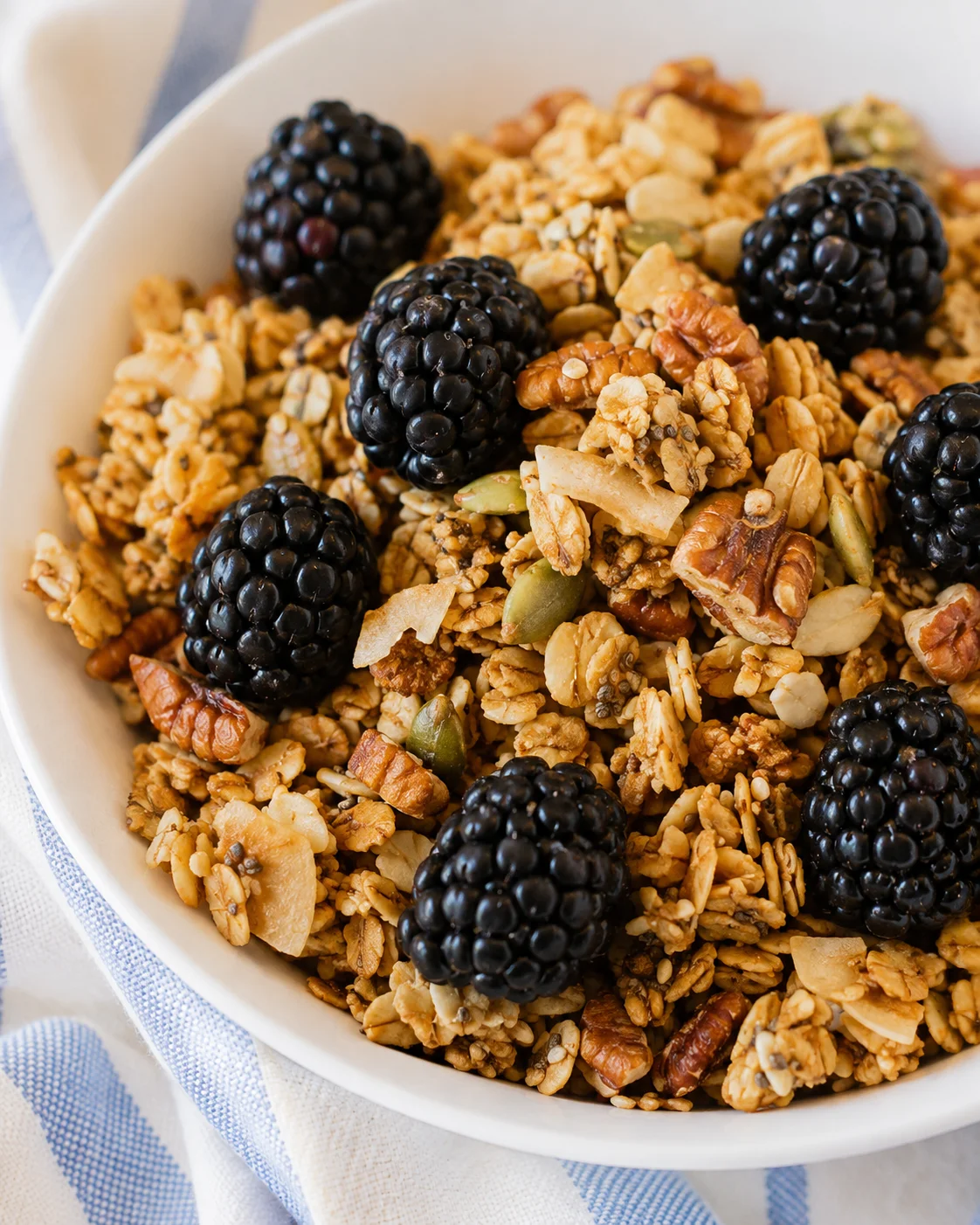 Healthy Gluten-Free Granola Recipe Crunchy homemade granola with blackberries in a white bowl.