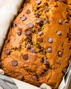 Close top view of a pumpkin chocolate chip bread in a parchment-lined pan