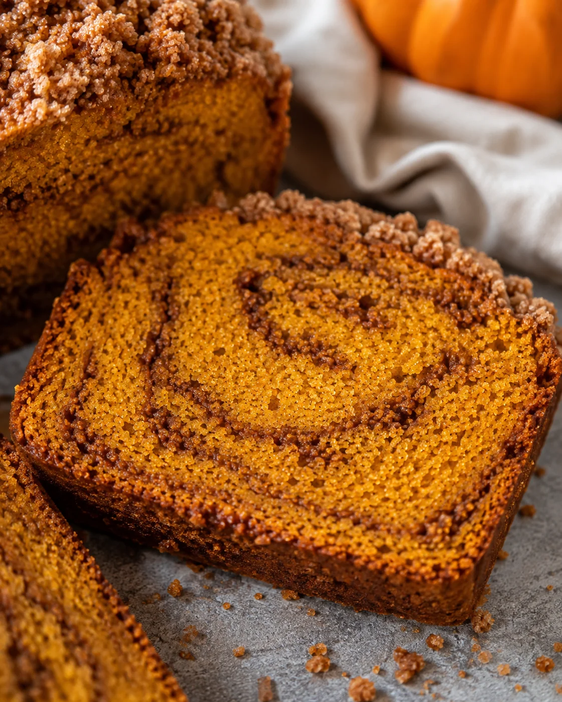 Slice of snickerdoodle pumpkin bread showing interior swirl and crumble edges